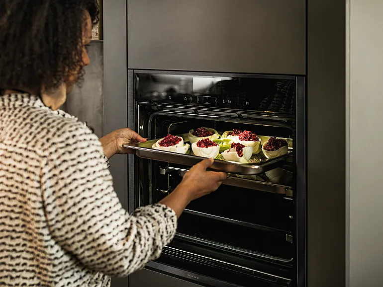 Backblech wird in einen hoch eingebauten Backofen geschoben