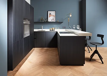 Kleine schwarze Küche mit graublauer Wand