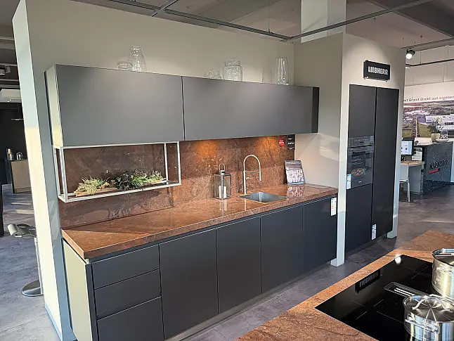 Designküche mit Organicglas-Fronten Naturstein-Arbeitsplatten und Kochinsel