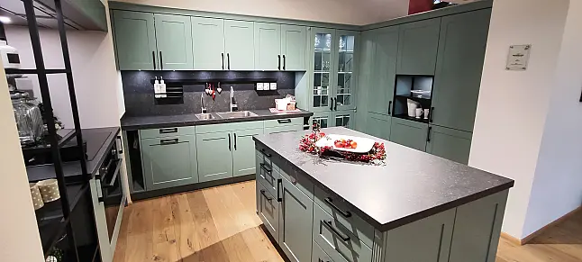 Landhausküche mit Sonderlackierung, Insel mit Weidekörbe und Pilaster und beleuchtete Glasvitrine mit Sprossen.