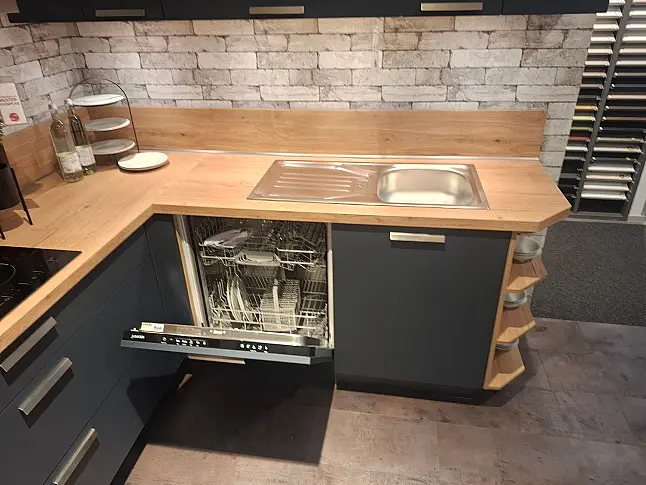Moderne L-Ausstellungsküche in mattem Fjordblau kombiniert mit Arbeitsplatten in Eiche Sierra Nachbildung und eleganter LED-Nova Plus Beleuchtung. Inklusive Marken-Elektrogeräten von Leonard, Junker und Faber sowie Spüle, ab sofort abholbereit.