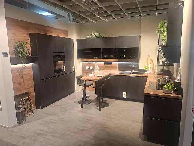 Moderne, elegante L-Küche mit wohnlicher Spachtelbetonoptik in Schwarz, kombiniert mit warmen Alpineiche-Akzenten und hochwertiger Lichtgestaltung.