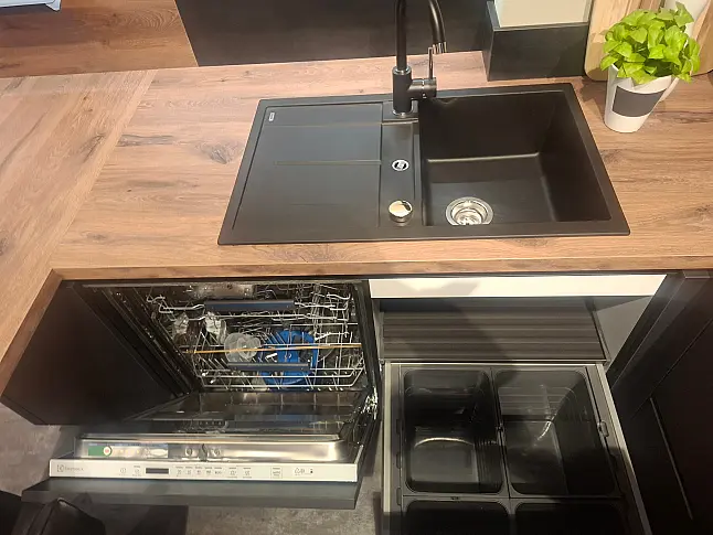 Moderne, elegante L-Küche mit wohnlicher Spachtelbetonoptik in Schwarz, kombiniert mit warmen Alpineiche-Akzenten und hochwertiger Lichtgestaltung.