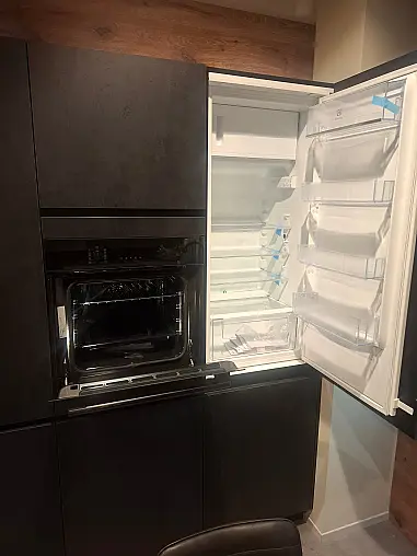 Moderne, elegante L-Küche mit wohnlicher Spachtelbetonoptik in Schwarz, kombiniert mit warmen Alpineiche-Akzenten und hochwertiger Lichtgestaltung.