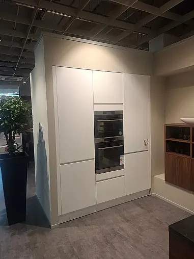 Moderne, elegante L-Küche in mattem Kristallweiß mit hochwertiger Geräteaustattung und Nischenverkleidung in Nussbaum