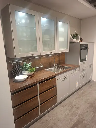 Elegante Küchenzeile mit hochwertigen Fronten in Perlgrau und warmen Alteiche-Akzenten.
