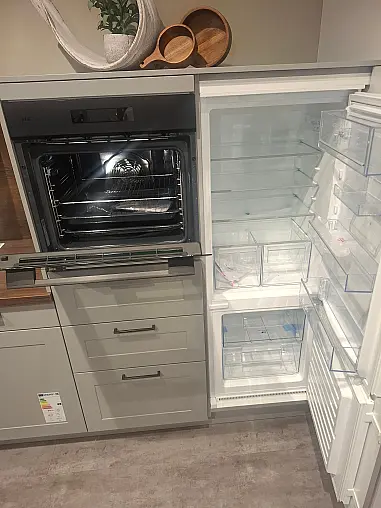 Elegante Küchenzeile mit hochwertigen Fronten in Perlgrau und warmen Alteiche-Akzenten.