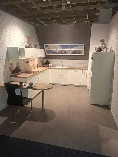 Elegante L-Küche in Weiß matt mit warmen Holz-Akzenten, inklusive Highboard-Elementen und gemütlichem Sitzbereich