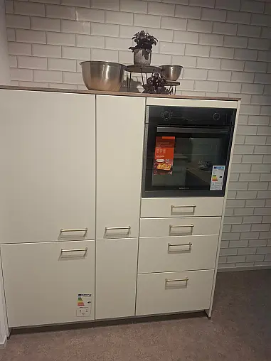 Elegante L-Küche in Weiß matt mit warmen Holz-Akzenten, inklusive Highboard-Elementen und gemütlichem Sitzbereich