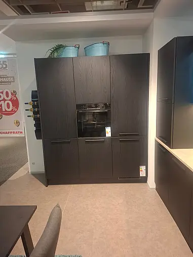Elegante, geradlinige Küche in Eiche Nero mit integriertem Essplatz und stimmungsvoller LED-Beleuchtung