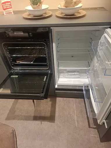 Moderne L-Küche in Quarzgrau supermatt mit Asteiche-Akzenten, integrierter LED-Beleuchtung und angeschlossenem Esstisch