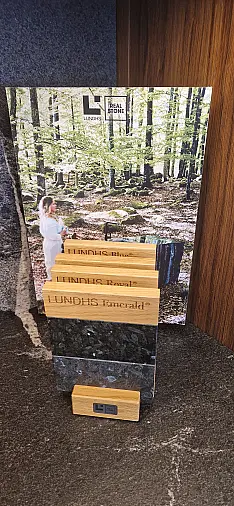 Edle Nußbaumfurnierfront grifflos, belegt mit brasilianischem Naturstein 2 m massiv und flächenbündig eingelassener Feinsteinspüle sowie Kochinsel mit flächenbündigem Siemens Induktionskochfeld.