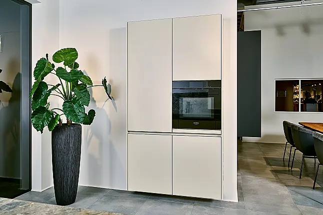 Koje 11 KL: Beige grifflose Küche mit Vitrinenschränken und Keramik Arbeitsplatte