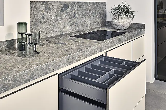 Koje 11 KL: Beige greeploze keuken met vitrinekasten en keramisch werkblad