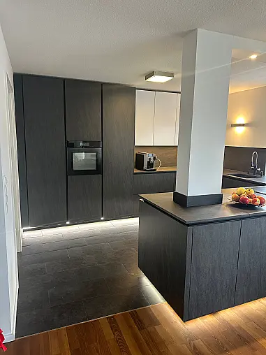 Designküche – Black Star Keramik &amp; Polarweiß Exklusive Fronten in Black Star Keramik, kombiniert mit Echtglas-Oberschränken in Polarweiß. Edles, puristisches Design mit LED-Sockelbeleuchtung und hochwertiger Ausstattung.