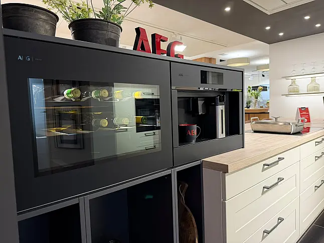 Häcker concept130 Landhausküche in Crema-Magnolie mit Halbinsel – AEG-Geräte inkl. Deckenlüfter, Weinkühler &amp; Kaffeevollautomat | Ausstellungsküche