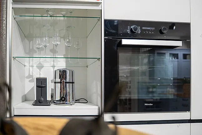 Häcker concept130 grifflose Küche in Kristallweiß – L-Form mit Riffelglas-Vitrinen, Miele &amp; AEG Induktion | Ausstellungsküche