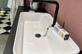 weißes Waschbecken mit schwarzer Armatur