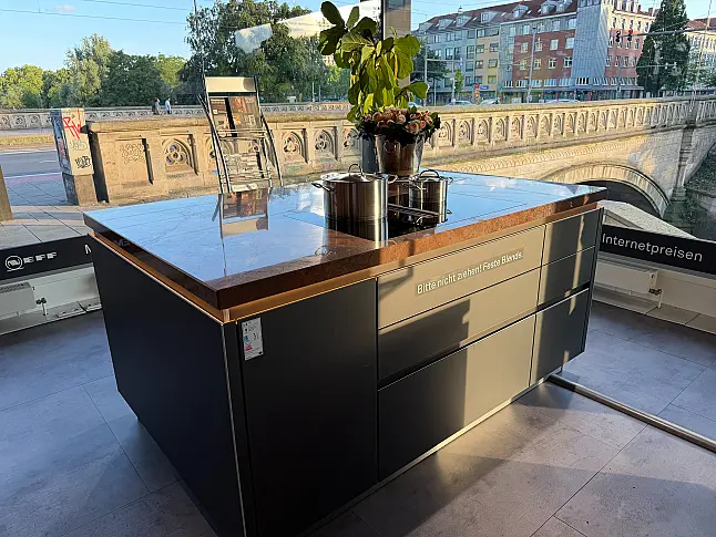 Designküche mit Organicglas-Fronten Naturstein-Arbeitsplatten und Kochinsel