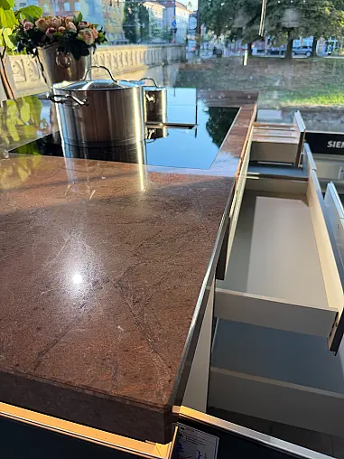 Designküche mit Organicglas-Fronten Naturstein-Arbeitsplatten und Kochinsel
