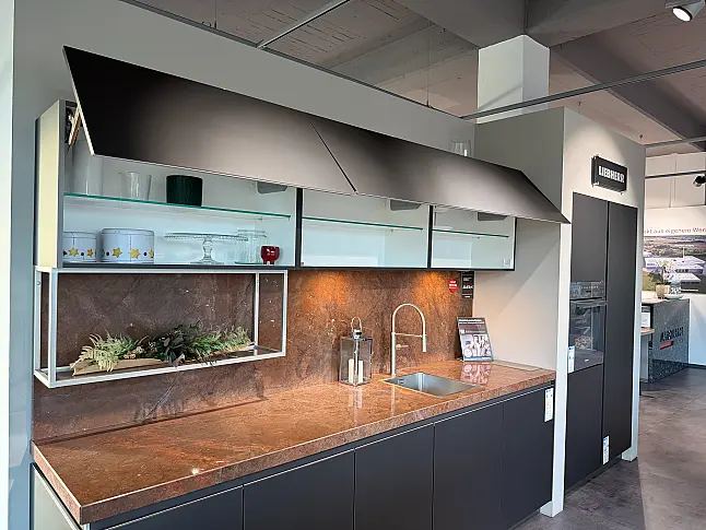 Designküche mit Organicglas-Fronten Naturstein-Arbeitsplatten und Kochinsel