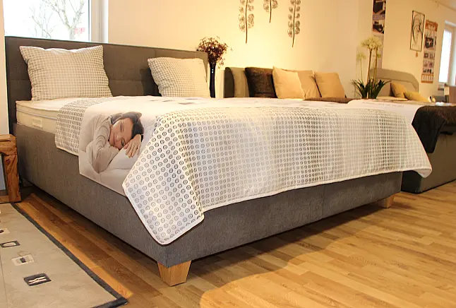 Hohes gemütliches Bett mit Kopfteil in klassischem Grau