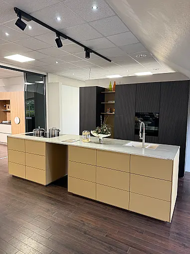 Moderne, grifflose Ausstellungsküche in zwei Farben mit Insel und Miele Geräten