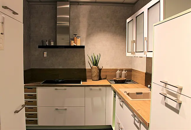 Gemütliche L-Küche mit extra Geräte-Hochschrank für den Kühlschrank in moderner Kombination: Krsitallweiß matt, mit Massiver Steinplatte sowie Farbakzenten in Pastellgrün