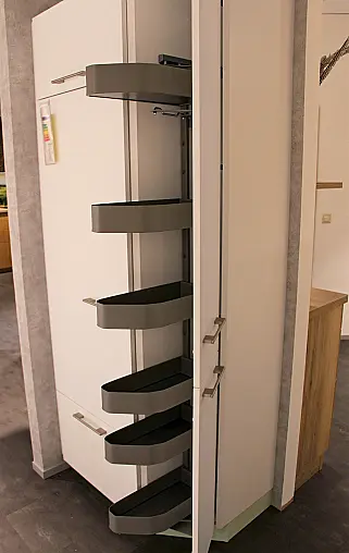 Gemütliche L-Küche mit extra Geräte-Hochschrank für den Kühlschrank in moderner Kombination: Krsitallweiß matt, mit Massiver Steinplatte sowie Farbakzenten in Pastellgrün