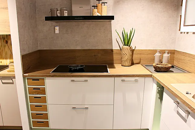 Gemütliche L-Küche mit extra Geräte-Hochschrank für den Kühlschrank in moderner Kombination: Krsitallweiß matt, mit Massiver Steinplatte sowie Farbakzenten in Pastellgrün