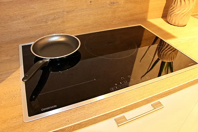 Gemütliche L-Küche mit extra Geräte-Hochschrank für den Kühlschrank in moderner Kombination: Krsitallweiß matt, mit Massiver Steinplatte sowie Farbakzenten in Pastellgrün