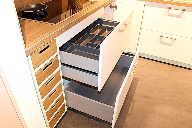 Gemütliche L-Küche mit extra Geräte-Hochschrank für den Kühlschrank in moderner Kombination: Krsitallweiß matt, mit Massiver Steinplatte sowie Farbakzenten in Pastellgrün