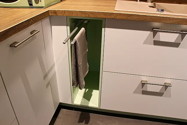 Gemütliche L-Küche mit extra Geräte-Hochschrank für den Kühlschrank in moderner Kombination: Krsitallweiß matt, mit Massiver Steinplatte sowie Farbakzenten in Pastellgrün