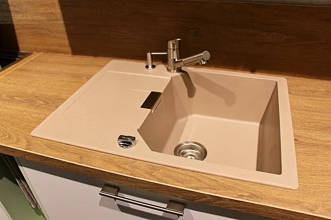 Gemütliche L-Küche mit extra Geräte-Hochschrank für den Kühlschrank in moderner Kombination: Krsitallweiß matt, mit Massiver Steinplatte sowie Farbakzenten in Pastellgrün