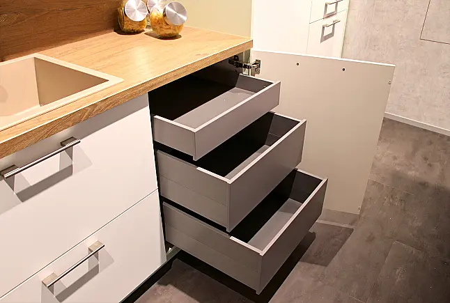 Gemütliche L-Küche mit extra Geräte-Hochschrank für den Kühlschrank in moderner Kombination: Krsitallweiß matt, mit Massiver Steinplatte sowie Farbakzenten in Pastellgrün