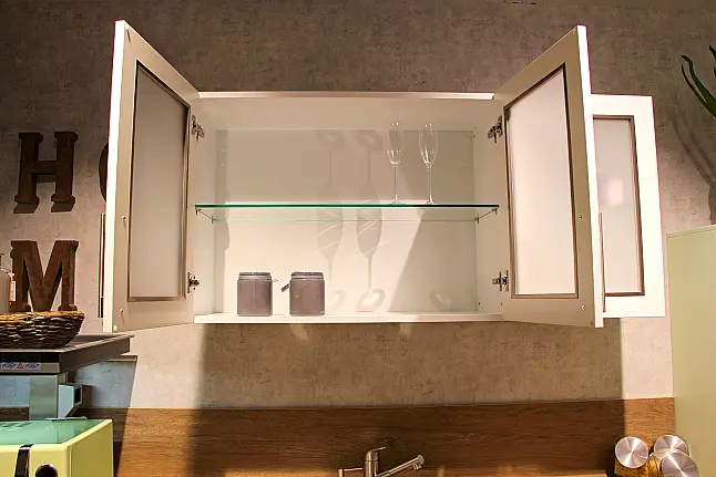 Gemütliche L-Küche mit extra Geräte-Hochschrank für den Kühlschrank in moderner Kombination: Krsitallweiß matt, mit Massiver Steinplatte sowie Farbakzenten in Pastellgrün