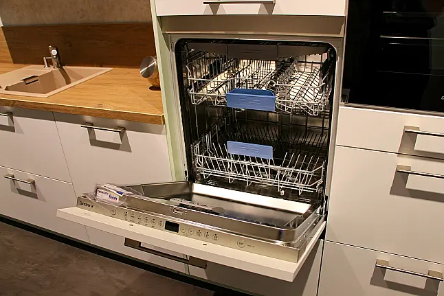 Gemütliche L-Küche mit extra Geräte-Hochschrank für den Kühlschrank in moderner Kombination: Krsitallweiß matt, mit Massiver Steinplatte sowie Farbakzenten in Pastellgrün