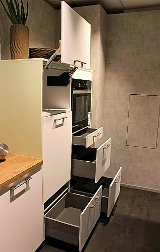 Gemütliche L-Küche mit extra Geräte-Hochschrank für den Kühlschrank in moderner Kombination: Krsitallweiß matt, mit Massiver Steinplatte sowie Farbakzenten in Pastellgrün