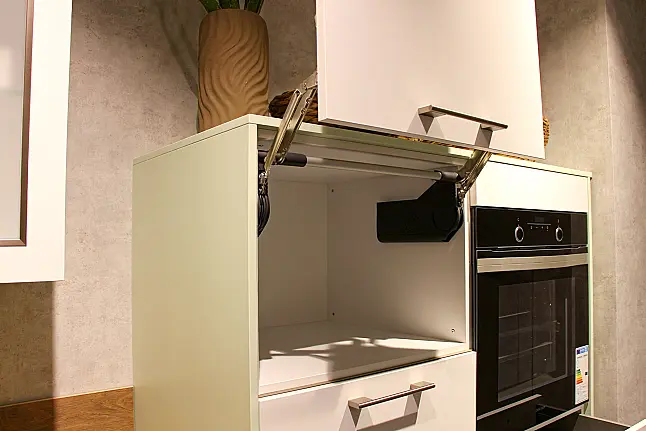 Gemütliche L-Küche mit extra Geräte-Hochschrank für den Kühlschrank in moderner Kombination: Krsitallweiß matt, mit Massiver Steinplatte sowie Farbakzenten in Pastellgrün