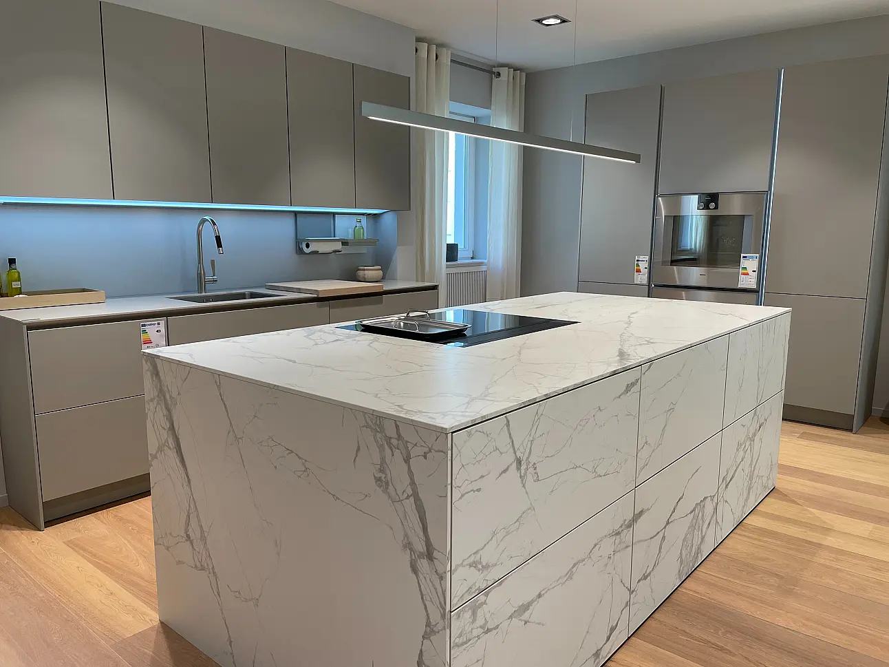 SieMatic SLX mit großer Marmor-Keramikinsel und kieselgrauer Zeile in Berlin