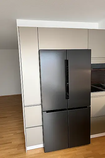 Moderne Designküche mit hochwertigen Polimerglas-Fronten in Sandgrau Metallic. Die warme Resopal-Arbeitsplatte in Alteiche Natur sorgt für einen edlen Kontrast und eine natürliche Ausstrahlung. Besondere Akzente setzt die elegante LED-Griffbeleuchtung.