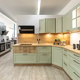 „Avocado trifft Chalet-Eiche“ – außergewöhnliche Landhausküche in L-Form mit lackierten Fronten