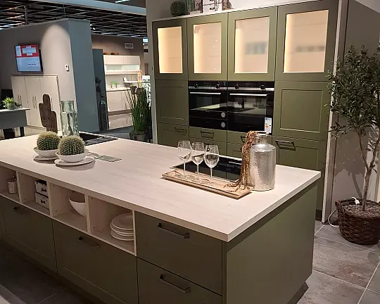 Moderner Landhausstil neu interpretiert:  Küche mit freistehender Insel, satinierten Glas-Hängeschränken und hochwertigen Siemens-Einbaugeräten - Frame Lack - A20 Lack, Olive softmatt / B21 Kiruna Birke (Programm F30) - Koje 200