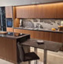 Edle Nußbaumfurnierfront grifflos, belegt mit brasilianischem Naturstein 2 m massiv und flächenbündig eingelassener Feinsteinspüle sowie Kochinsel mit flächenbündigem Siemens Induktionskochfeld.