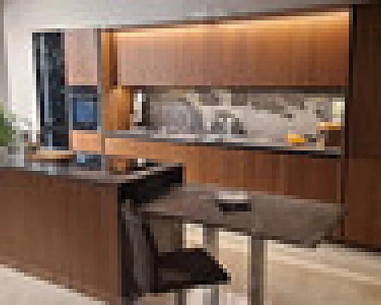 Edle Nußbaumfurnierfront grifflos, belegt mit brasilianischem Naturstein 2 m massiv und flächenbündig eingelassener Feinsteinspüle sowie Kochinsel mit flächenbündigem Siemens Induktionskochfeld. - Patrizia Nußbaum mit vertikaler Rillung, und Hartgesteinarbeitsplatten Tisch und Rückwand