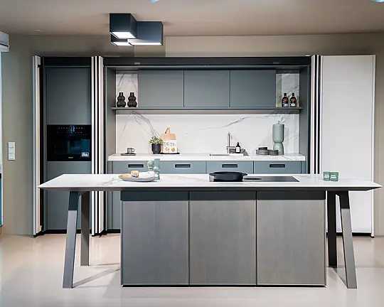 Elegante Küche mit Pocket Doors und Insel mit Holz und angenehmer Farb-Kombi - SensiQ muschelweiß feinmatt AFP + Kobaltgrün samtmatt AFP + Eiche elegant perlgrau