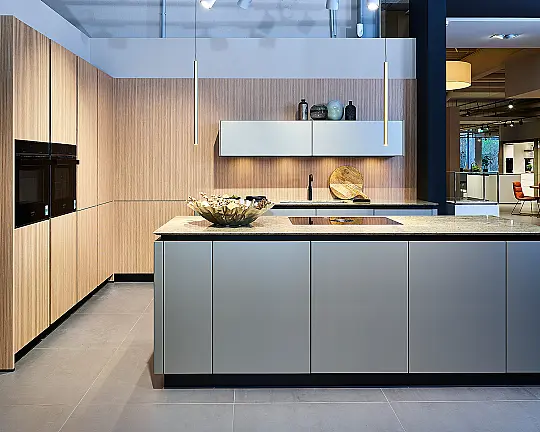 Koje 28 KL: Eckküche in Eiche und Taupe mit Naturstein Arbeitsplatte - Lineo Rillenoptik Eiche natur & Smartglas Polymerglas Taupe metallic matt