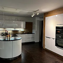 Sehr elegante gerundete, teilweise grifflose Küche mit Halbinsel in Hochglanz weiß mit schwarzer Steinplatte