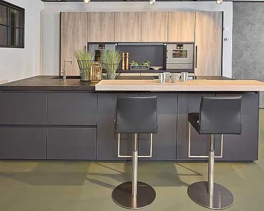 Koje 24 KH: Schwarze Inselküche mit Holz und Keramik Arbeitsplatte - Glasline matt Lavaschwarz und Modena Esche Nordic