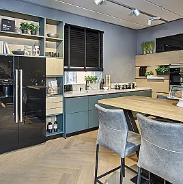 Koje 65 KH: Grüne grifflose Eckküche mit hellem Holz und Komposit Arbeitsplatte